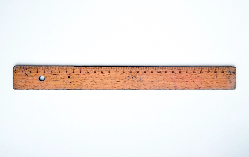 Righello di legno consumato appoggiato su un piano di scrivania chiaro