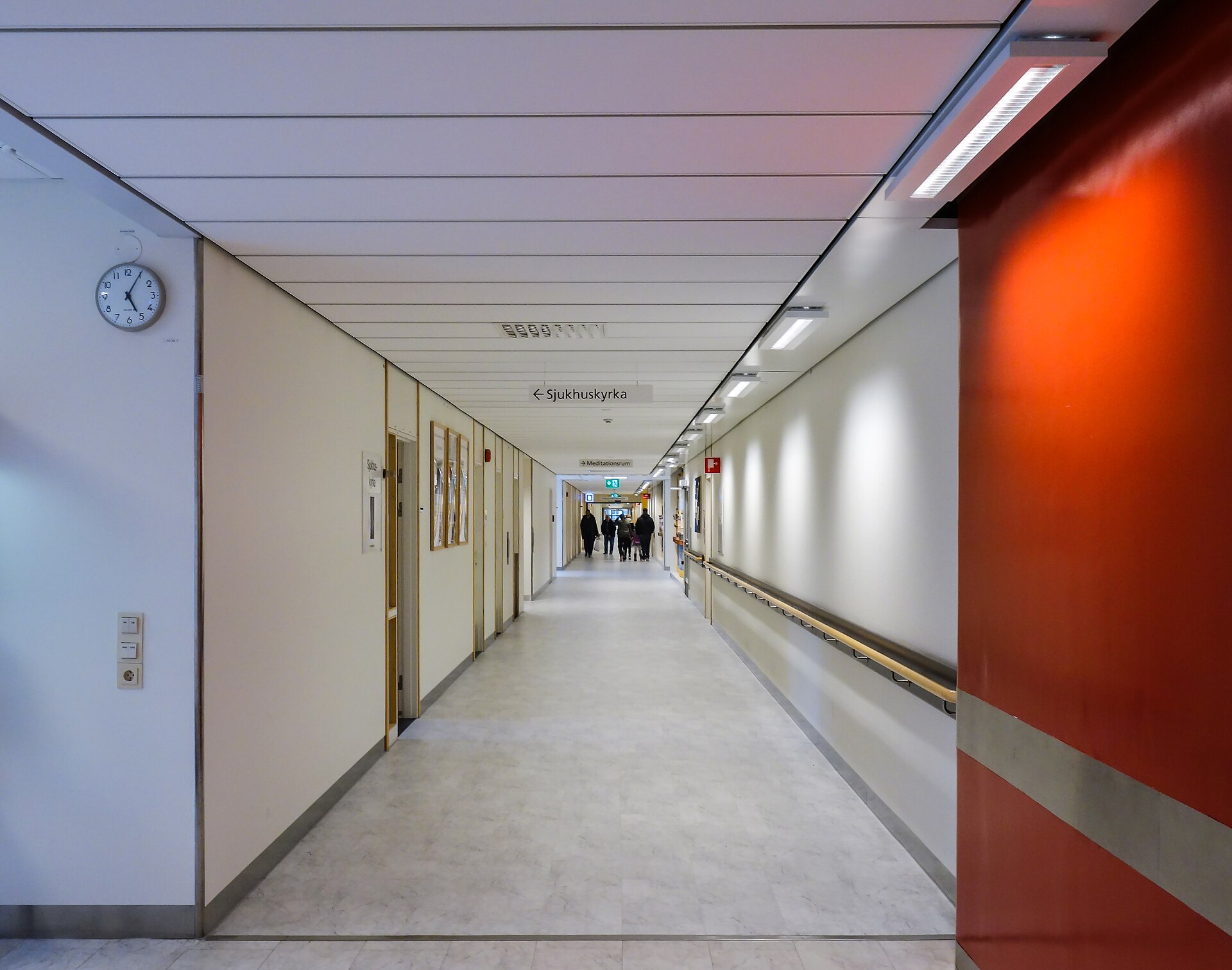 Corridoio di ospedale con finestra in fondo e luce naturale sul pavimento chiaro