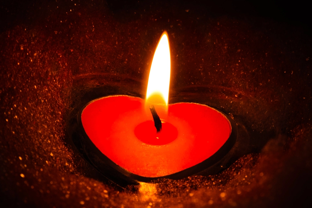Candela accesa su un piano di legno in una stanza dalla luce molto bassa